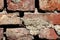 Texture of old cracked dilapidated red bricks wall partially covered with dry concrete mixed with small grain gravel