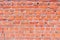 Texture of old crumbling red brick wall with cement mortar. Background of red burnt clay brick with cracks