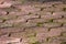 Texture of old dilapidated heavily used washed out stone tiles sidewalk divided by small grain gravel and moss growing between