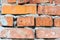 Texture of an old orange brick wall with cracks. Clay brick background with cracks and cement mortar with gypsum in the daytime