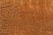 Texture of orange brown genuine leather close-up, with embossed scales reptiles, fashion trend pattern, wallpaper or