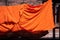 Texture of orange robe of a buddhist monk or novice hanged on wire