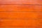 The texture of orange wood floor. They are arranged in rows beautifully. It is a beautifull patterned surface with shiny dark