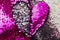Texture of pink and silver sequins with a heart.