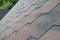 The texture of the roof with bituminous coating. Rough bituminous mosaic of red and brown flowers. Waterproof roofing