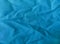Texture of soft turquoise blue cotton fabric with shabby and wrinkled surface