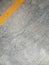 Texture surface of grey concrete road with scratches, indents and chipped with yellow lane divider line with copy space.