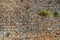 Texture of Vertical ancient stone wall with plants. Surface from grey and orange stones. Old wall in Macedonia