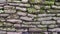 The texture of the wall is made of natural stone flagstone covered with moss. Ancient masonry, vintage background. The wall made