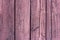 Texture of weathered wooden lining boards with peeling violet paint and rusty nail heads. Vignette.