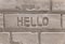 Texture of a white wall of bricks and the english word hello carved in center.