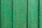 Texture of a wooden board in green. A crackling green paint on the vertical wooden boards. Vertical parallel lines