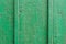 Texture of a wooden board in green. A crackling green paint on the vertical wooden boards. Vertical parallel lines