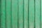 Texture of a wooden board in green. A crackling green paint on the vertical wooden boards. Vertical parallel lines