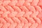 Textured background. Knitted fabric in peach color in the form of intertwined braids. Top view