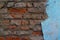 Textured background of old red brick wall with part of destroyed blue plaster, copy space for text