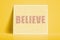 textured card with the word believe