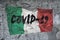 On the textured concrete wall with the Italian flag, the inscription: COVID-19. Concept: coronavirus and pandemic, natural disaste