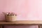 Textured pastel pink wall copy space. Monochrome empty wall in kitchen with minimalist wooden table and flowers in a wricked vine