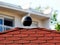 Textured red asphalt shingle roof detail in low angle view with blurry background