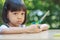 Thai Asian girl,aged 4 to 6 years old, looks cute, sitting outdoors in the garden Holding scissors in her hand Eyes staring