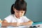 Thai Asian kid girls, aged 4 to 6 years old, look cute and bright. Healthy Sitting in the house studying She is writing a book and