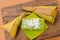 Thai dessert sticky rice wrapped in banana leaf on wood background.