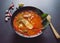 Thai food background concept. Dish of Thailand cuisine. Tom yum soup in black dish and soft focus chilis, galic on table