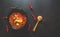 Thai food background concept. Dish of Thailand cuisine. Tom yum soup in black dish, wooden spoon and chilis