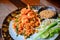 Thai food, stir fry rice noodles with shrimps, tofu, vegetable and crushed peanuts or pad thai on wooden table background