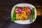 Thai Fried Noodles `Pad Thai ` with shrimp and vegetables on the white ceramic dish decorated with orchid put on dark wooden table