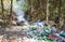 Thai garbage recycle pile plastic bottle and glass bottle in the nature with incineration waste burning cause air pollution or