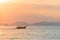 Thai long-tailed traditional boat floats on a beautiful colored sunset on the sea against the silhouette of the mountains in