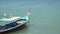 Thai longtail boat passing wait tourists in the sea on tropical beach, off the coast of Phuket Thailand