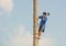 Thai man sitting on tree trunk cutting big palm tree with an axe under blue sky