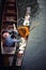 Thai monk on wood boat receiving food from woman offering