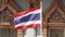 The Thai national flag flutters in front of the entrance to a Buddhist temple