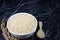 Thai parboiled rice  in white ceramic bowl and wooden spoon on dark marble table