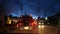 Thai songthaew bus with lit headlights traveling along night street during rain season. View through glass of car in