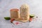 Thai sticky rice in a woven bamboo basket on a wooden panel with chilies, lime, and garlic