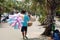 Thai street vendor selling bread and cotton candy on a street. Walking hawker guy with lots of food from the back.