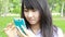Thai student teen beautiful girl using her smart phone sitting in park.
