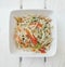 Thai style stir fried bean sprouts with chicken minced  green onions garlics and tomatoes in a square white bowl