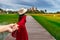 Thai tourists join hands along a wooden bridge in the middle of a rice field with a temple in the background