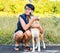 A Thai Woman with her dog playing on the grass field ,they are look very happy and funny.