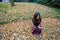 Thai woman kneeling on ground surrounded by leaves in the fall l
