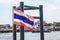 Thailand National Flag at boat pier with beautiful summer view of Thai riverside naval commuter traffic background in Chao Phraya