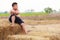 Thailand Rural Traditional Scene, Thai farmer shepherd boy sitting on dry straw stack pile in the farm. Thai Upcountry Culture