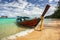 Thailand typical Long-tail boat on clear azure green sea, sky with small clouds above, golden beach on right, Koh Kradan