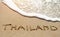 Thailand written on the sand beach near sea - travel holiday concept